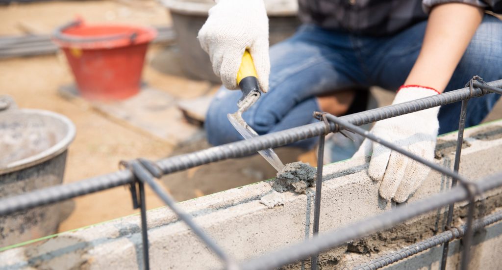 Bricklayer worker installing brick masonry on exterior wall with trowel putty knife